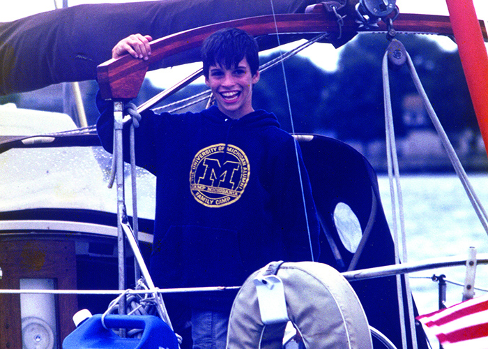 Young Caucasian teenage male wearing a navy hoodie on a sailboat 
