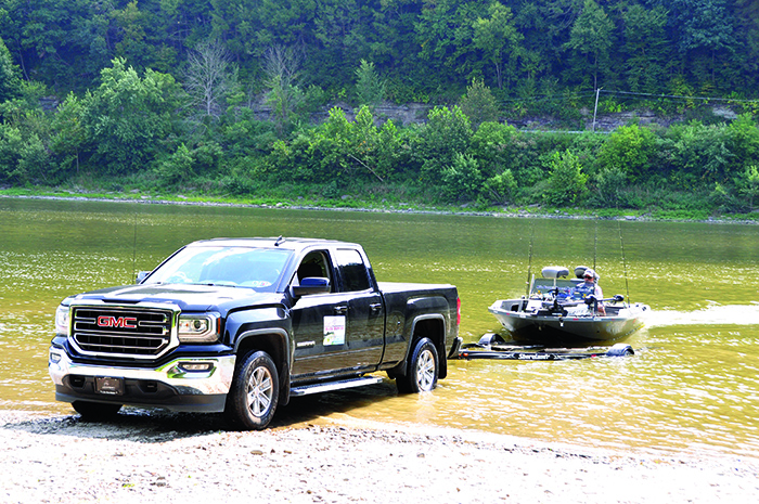 Black GMC truck compensating for a current while launching a black fishing boat in the water.