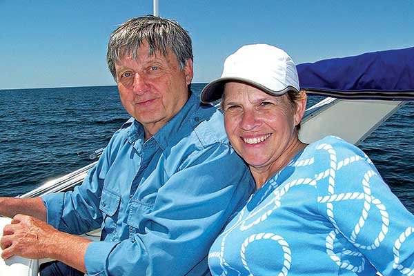 A mature white couple, a man and a woman, are smiling as they ride a boat during the day