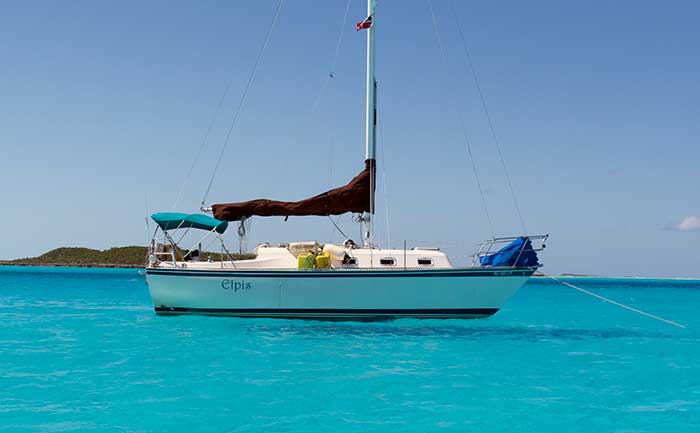 A sailboat anchored in turquoise water with the word Elpis on the side