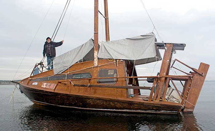 A man stands atop his home-built boat