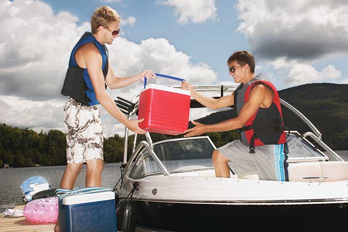 Two men loading a cooler on boat