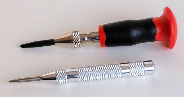 Close-up of two center punch tools one black with a red handle and one silver