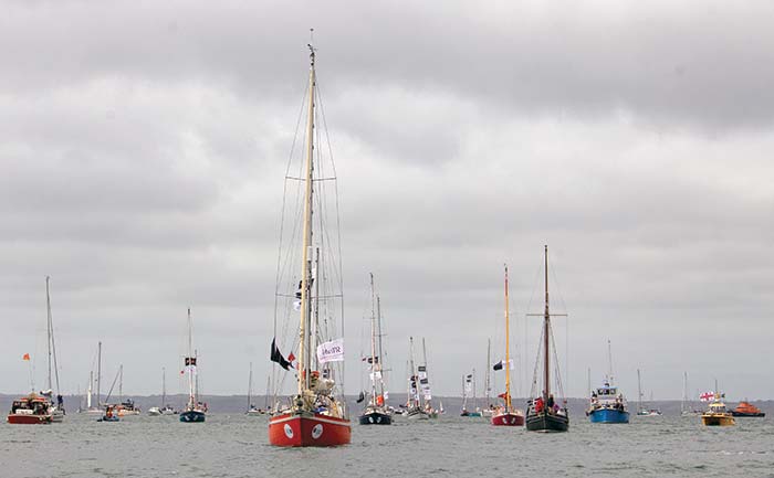 Group of colorful sailboats racing under coudy gray skies