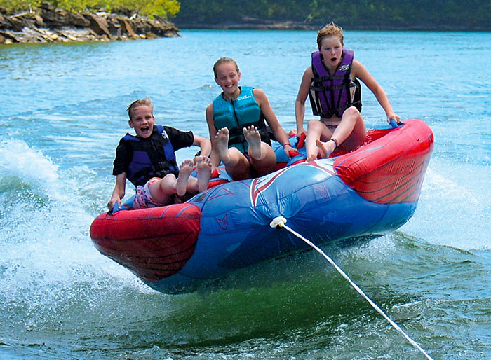 Three children being towed on a raft water toy
