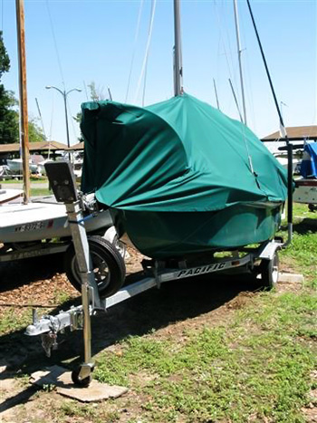 A well-fitted green boat cover on a trailer