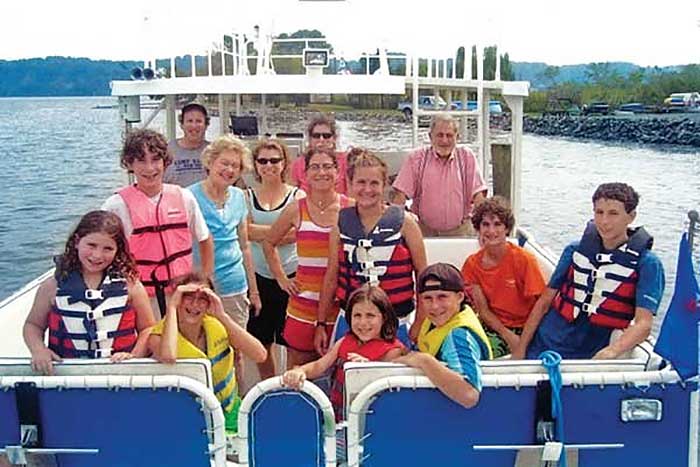 Large family group posing for a photo aboard their large pontoon boat as it cruises down the river