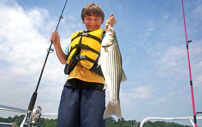 Young boy smiling and holding up his catch