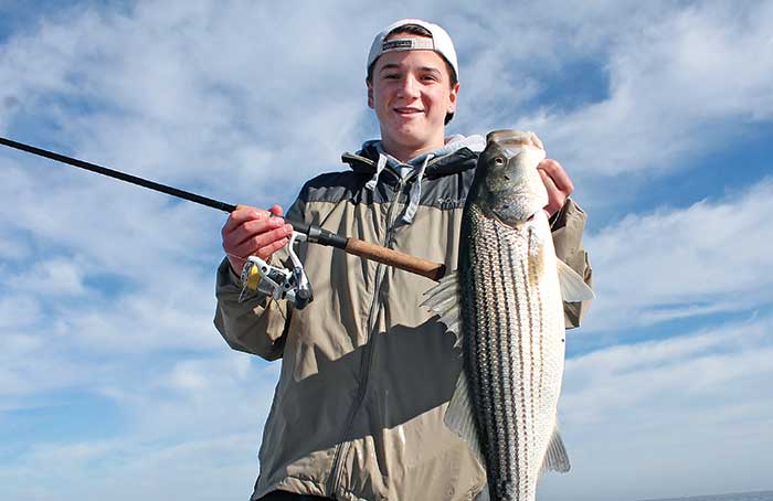 Boy holding his stripped bass catch