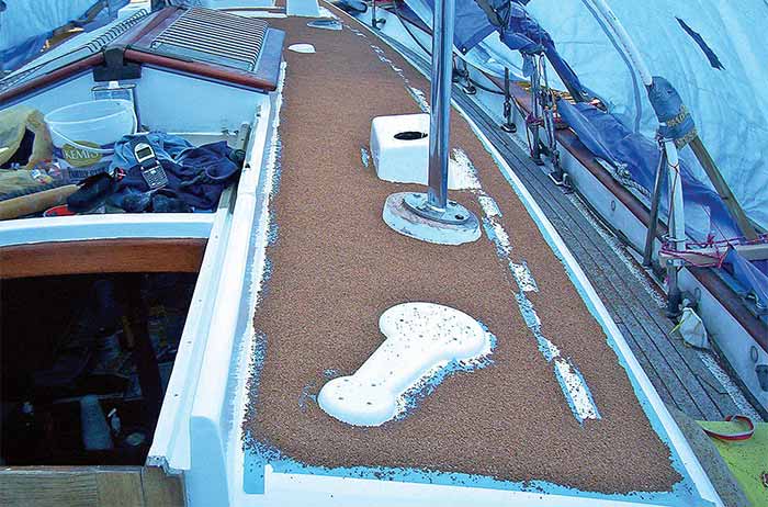 Close-up photo of boat deck surface finished paint with crack walnut shells and sand added to the wet paint
