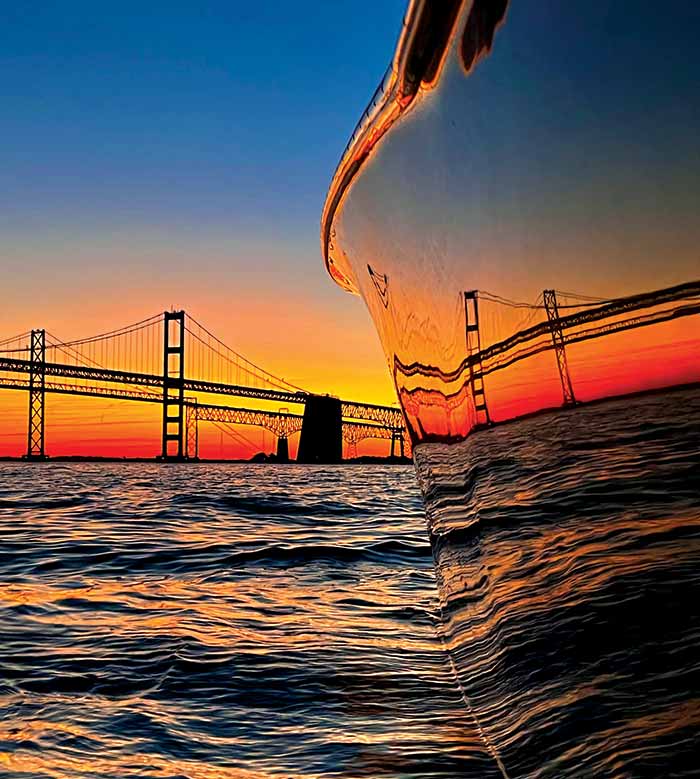 Photo Contest Scenic Finalist: Image of a beautiful sunset, the Chesapeake Bay Bridge, and a boat reflecting the autumn colors on the water