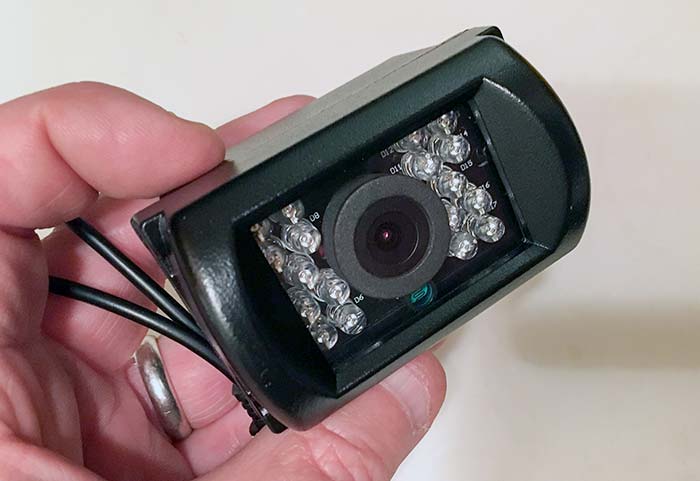 A hand holds a small black camera 