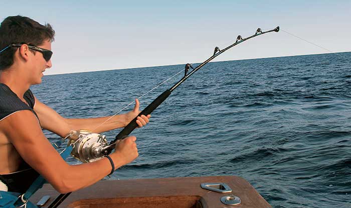 A man is reeling in his fishing rod