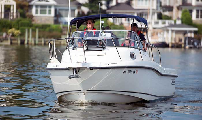Three people smile as they are underway in a white powerboat
