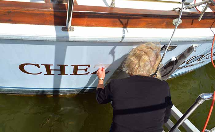 Woman installing a boat name on the stern of a boat