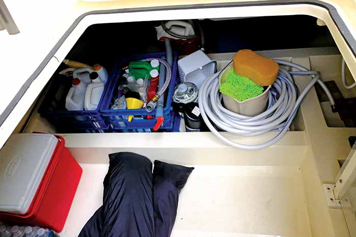 Boat storage under deck with cleaning solutions, hose, bucket, sponges, cooler and waders