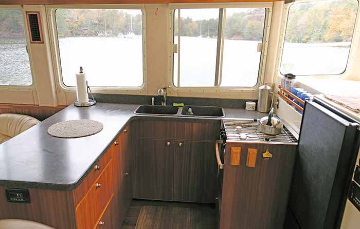 Galley kitchen with sink and stove and windows looking out onto the water