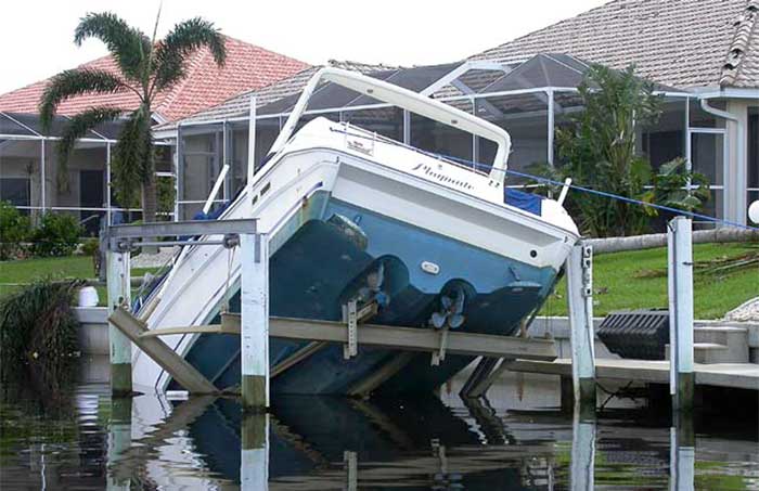 The bow of a powerboat is submerged under water at a home dock. The back of the boat is extended in the air