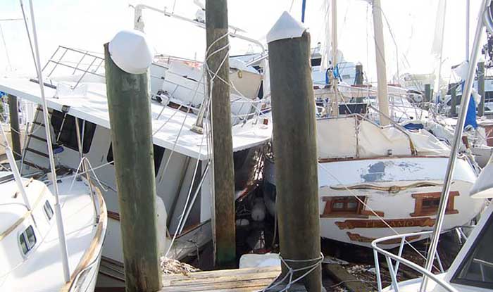 A damaged pile of boats all crashed into one another and broken wooden docks