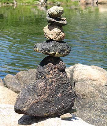 A stack of 5 small rocks with a body of water in the background