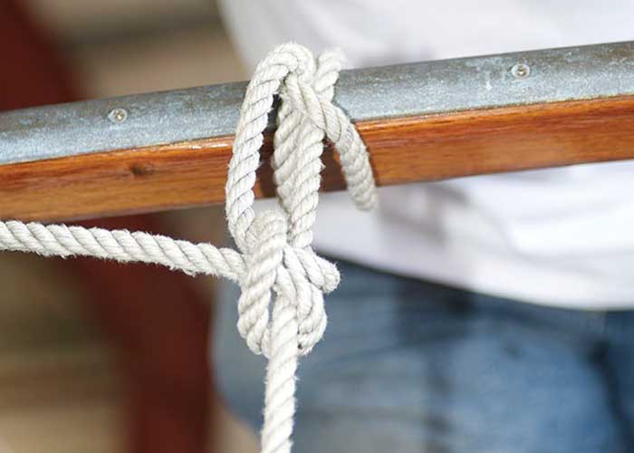 Using a clove hitch knot to secure the boat fender to the rail