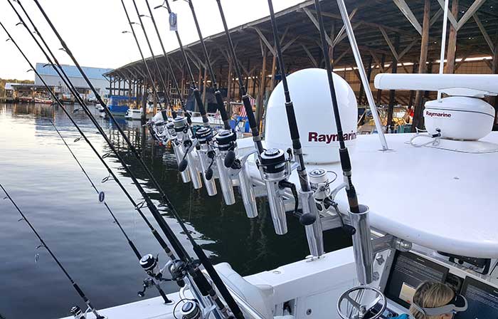 Fishing boat equipped with multiple rod holders docked at marina