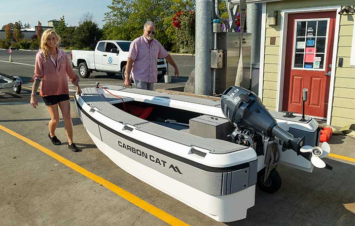 Woman and man carrying a Carbon Cat boat tender through a parking lot