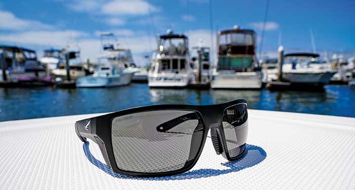 A pair of sunglasses sitting on the deck of a boat with other large boats in the background