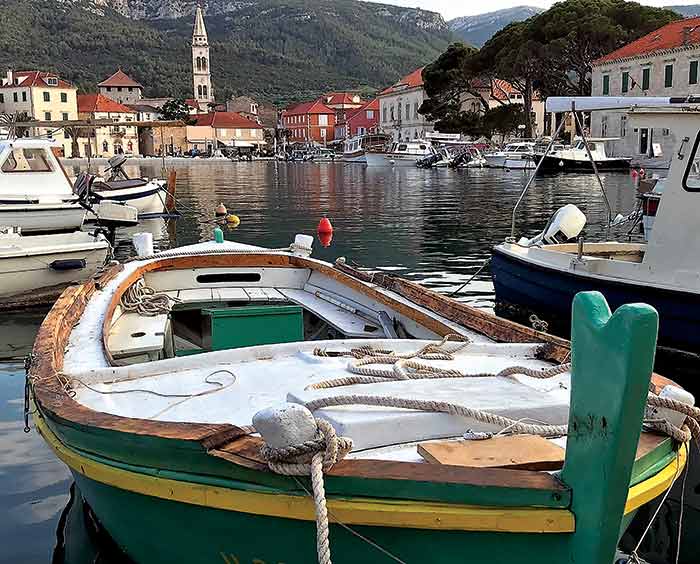 Green and yellow fishing boat docked at the village of Milna in Croatia
