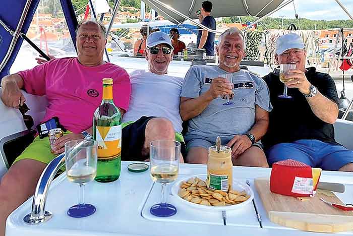 Four men enjoying cheese, crackers and wine aboard a charter boat cruising Croatia