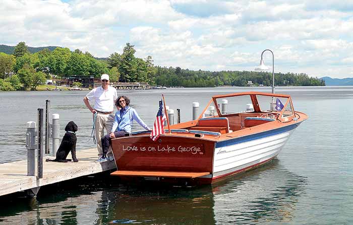Ron and Kathy Miller and their poodle next to their Lyman runabout docked on Lake George