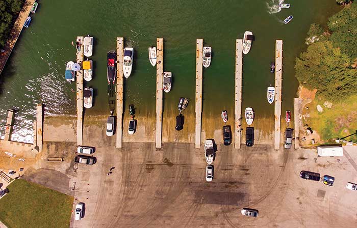 Aerial view of a boat launching area with 9 boat ramps and various boats and vehicles parked around the ramp areas