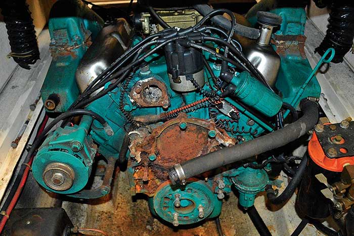 Close-up of green-colored boat engine with hose, wires and some rust and corrosion visible