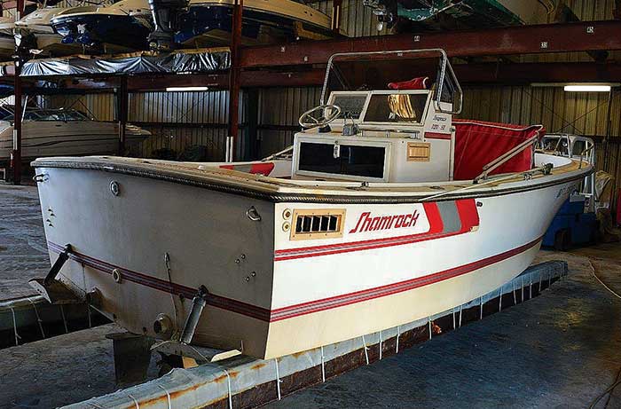 White with red trim center-console boat sitting on a trailer in a warehouse