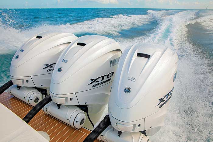 Three of Yamaha's 450-hp V8 XTO Offshore outboards running on the stern of a powerboat with blue water churning in the background
