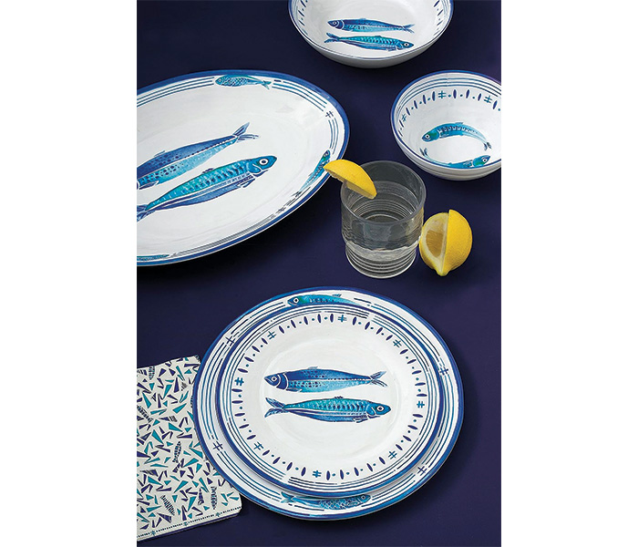 White set of dinnerware with blue fish set on a table.
