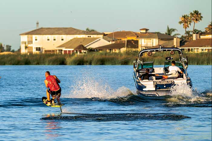 Photo Contest Action & Watersports Finalist: Image of man wearing an orange lifejacket wakeboarding while being towed by a powerboat