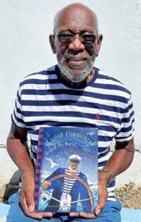 Older man standing wearing a blue stripped shirt and sunglasses hold open a children's book