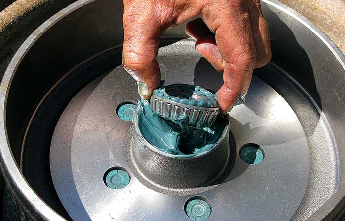 Hand holding a trailer wheel hub covered in grease