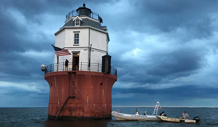 Two small boats anchored at a floating lighthouse in the Chesapeake Bay