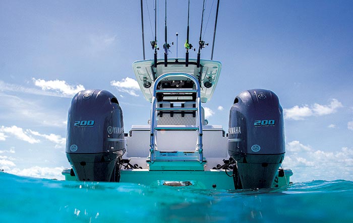 Rear view of a dual hull catamaran with two 200 horsepower outboard engines, a bimini top with fishing rods attched to it moored  in turquoise blue water