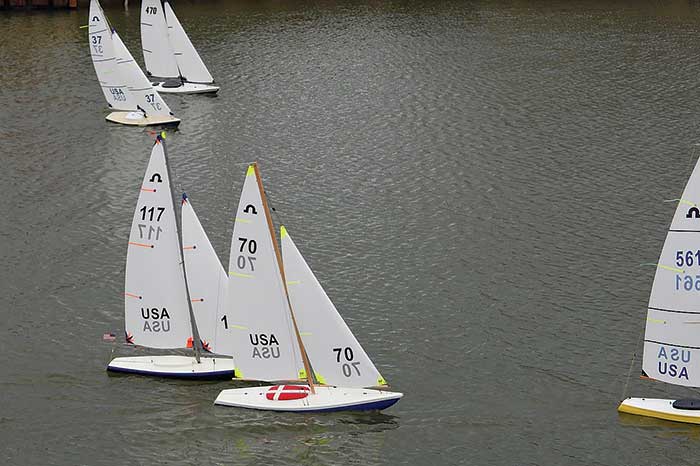 Several white radio-controlled sailboats on the water