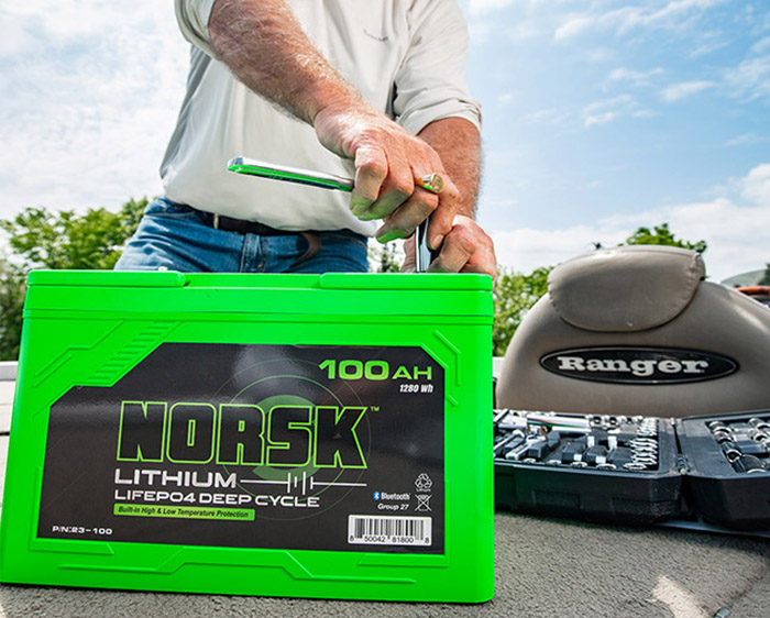 Green Norsk Lithium battery being installed on a boat by an adult male.