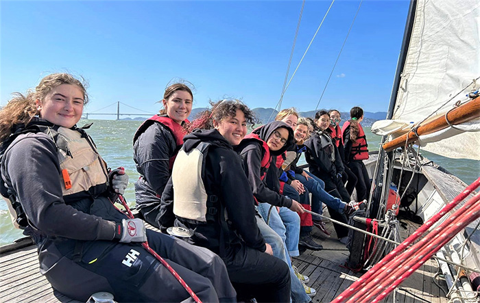 Nine members of female sea scout group sailing on the open waters.