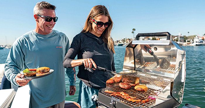 Middle-aged white male and female grilling cheese burgers on a boat
