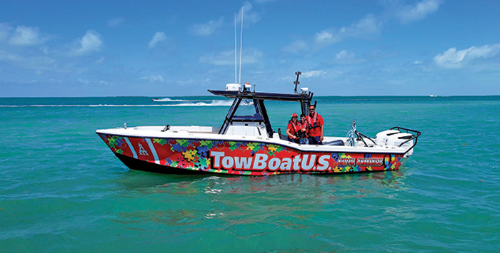 Family of three aboard their red TowBoatU.S. Islamorada 32-foot puzzle-piece-wrapped response vessel