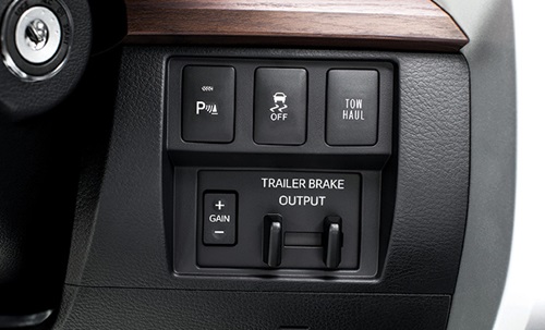 Controls, featuring trailer brakes, on a dashboard near key ignition.