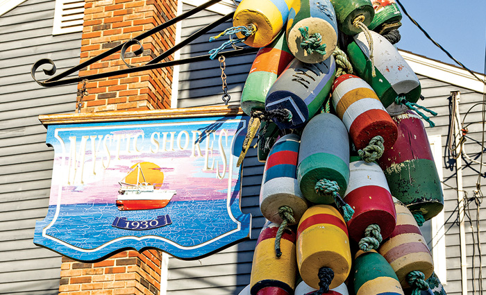Numerous colorful buoy's tied to a Mystic Shores sign.