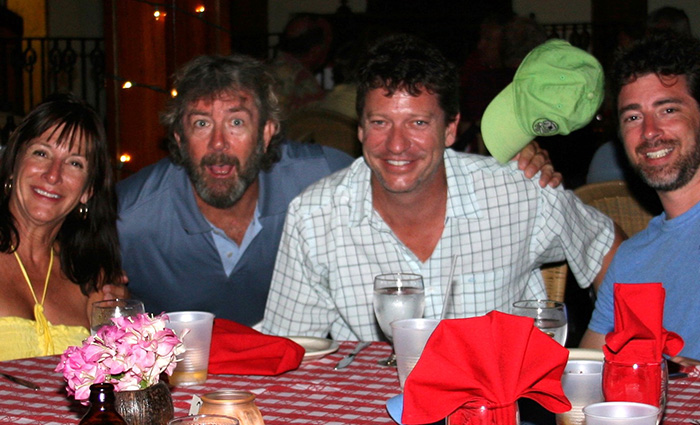 Three adult males and an adult female posing for a picture around a table at a restaurant.