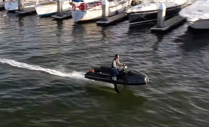 Adult male riding the black Valo personal motor craft and existing a harbor on open waters.